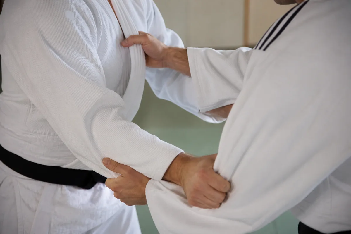 Deux judokas en judogi blanc et bleu au moment de la prise de garde sur un tatami